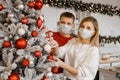 Close up portrait of family couple wearing face protective medical mask for protection from virus disease decorating christmas Royalty Free Stock Photo