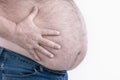 Fat man hand holding his big belly on a light background: typical photo for beer belly: Selective focus. Royalty Free Stock Photo