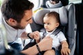 Close up portrait of young father securing baby in child seat of car