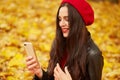 Close up portrait of female wearing red beret and leather jacket, model sitting on ground outside. Young attarctive woman spending