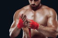 Close up portrait of fighter hands applying bondage tape on hands isolated on black background