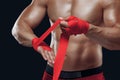 Close up portrait of fighter hands applying bondage tape on hands isolated on black background