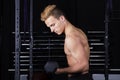 Close Up portrait of a fit young man lifting weights in gym on dark background. Royalty Free Stock Photo