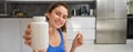 Close up portrait of fitness woman, girl workout from home, showing bottle of vitamins, dietary supplement pills