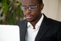 Focused African American CEO looking at laptop screen reading ne