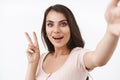Close-up portrait friendly beautiful caucasian woman taking selfie in kawaii pose, holding camera with extended arm and