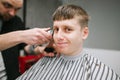 Close-up portrait of a funny barber shop customer, gets a haircut from a barber and looks into the camera with a funny face.