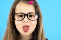 Close up portrait of a funny child school girl wearing looking glasses isolated on blue background