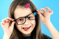 Close up portrait of a funny child school girl wearing looking glasses isolated on blue background