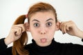 Close up portrait of funny girl holding her ears and sticking out tongue like a monkey Royalty Free Stock Photo