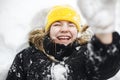 Close up portrait of funny happy teenage girl in yellow knitted hat playing with snow outdoors Royalty Free Stock Photo