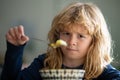 Close up portrait of funny kid eating. Sad boy eating healthy chicken noodle soup for lunch. Unhappy baby child taking Royalty Free Stock Photo