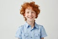 Close up portrait of funny little boy with orange hair and freckles mowing eyes, smiling and making silly faces for