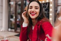 Close-up portrait of girl with gorgeous smile making selfie in red outfit. Outdoor photo of positive dark-haired lady