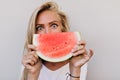 Close-up portrait of girl with gray eyes eating watermelon. Indoor photo of spectacular caucasian l