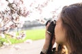 Portrait of girl making photo of flowering tree