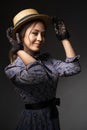 A close-up portrait of a girl standing in a dress in the style of the 1900s. He holds on to the hat with his hands Royalty Free Stock Photo