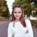 Close-up portrait of girl, teenager schoolgirl, in white knitted sweater, in summer in park. Happy smiles, emotions of