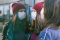 Close-up portrait of girls with medical masks. Against the background of a glass building with reflections. Concept on the topic