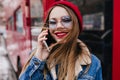Close-up portrait of glamorous girl in blue glasses talking on phone. Outdoor portrait of winsome c