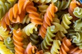 A close up portrait of a glass pot, jar or bowl full of spirelli in three different colors. The uncooked tricolore italian pasta Royalty Free Stock Photo