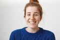 Close-up portrait of good-looking girl with freckles and natural red hair smiling nervously and chuckling, talking with