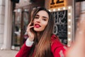 Close-up portrait of good-looking woman with dark hair making selfie on blur city background. Outdoor photo of sensual Royalty Free Stock Photo