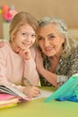 Close up portrait of grandmother with cute little girl doing homework