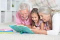 Close-up portrait of grandparents reading book with little granddaughter Royalty Free Stock Photo