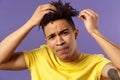 Close-up portrait of grimacing young focused guy looking in mirror at his haircut, need call his stylish or hairdresser