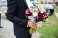 Close-up portrait of a groom holding a bouquet outdoor. Royalty Free Stock Photo