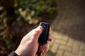 A close-up portrait of a hand of a person holding a car key pressing the unlock button with the thum. The remote control has Royalty Free Stock Photo