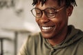 Close-up portrait of handsome African American man wearing glasses, smiling and looking down. positive, man`s look Royalty Free Stock Photo