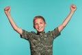 Close-up portrait of a blonde teenage boy in a green shirt with palm print posing against a blue studio background Royalty Free Stock Photo