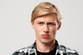 Close up portrait of handsome confident blond young man wearing casual plaid shirt looking in camera isolated on grey