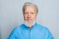 Close-up portrait of handsome gray-haired senior man unemotionally looking at camera on white isolated background. Royalty Free Stock Photo