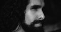 Close up portrait of handsome man with long dark wavy hair and beard. Confident man with unusual appearance stare