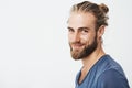 Close up portrait of handsome manly guy with beard posing in three quarters, looking in camera and happily smiling