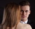 Close up portrait of a handsome man looking at the camera from behind the naked back of a sexy girl Royalty Free Stock Photo