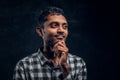 Portrait of a handsome young Indian guy wearing a checkered shirt holding hand on chin and looking at a camera with a Royalty Free Stock Photo