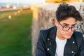 Close-up portrait of a handsome young man with glasses sitting and thinking outdoors Royalty Free Stock Photo