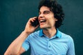 Close-up portrait of a handsome young man laughing and talking on the mobile phone with his girlfriend. Happy male with curly hair Royalty Free Stock Photo