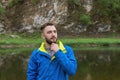 Close up portrait of handsome young man looking up thoughtfully touching his beard with hand on blurred natural background. Royalty Free Stock Photo