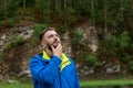 Close up portrait of handsome young man looking up thoughtfully touching his beard with hand on blurred natural background. Royalty Free Stock Photo