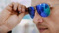 Close-up, portrait of Handsome young man trying on blue sunglasses at optical store, optician retail store. in glasses