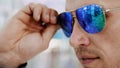 close-up, portrait of Handsome young man trying on blue sunglasses at optical store, optician retail store. in glasses