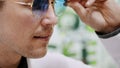 Close-up, portrait of Handsome young man trying on blue sunglasses at optical store, optics, optician retail store