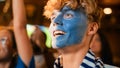 Close Up Portrait of a Handsome Young Soccer Fan with Painted Blue and White Face Standing in a Royalty Free Stock Photo