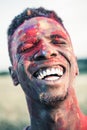 Happy african american man with colorful paint of face laughing with closed eyes at holi festival Royalty Free Stock Photo