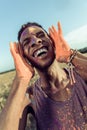 Happy african american man with colorful paint of face laughing with closed eyes at holi festival Royalty Free Stock Photo